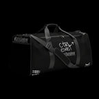 Black duffel bag with branding on a light gray background