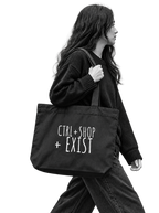 A woman in a black sweater and jeans carries a large black tote bag with the white text 'CTRL + SHOP + EXIST' on the front,model walk