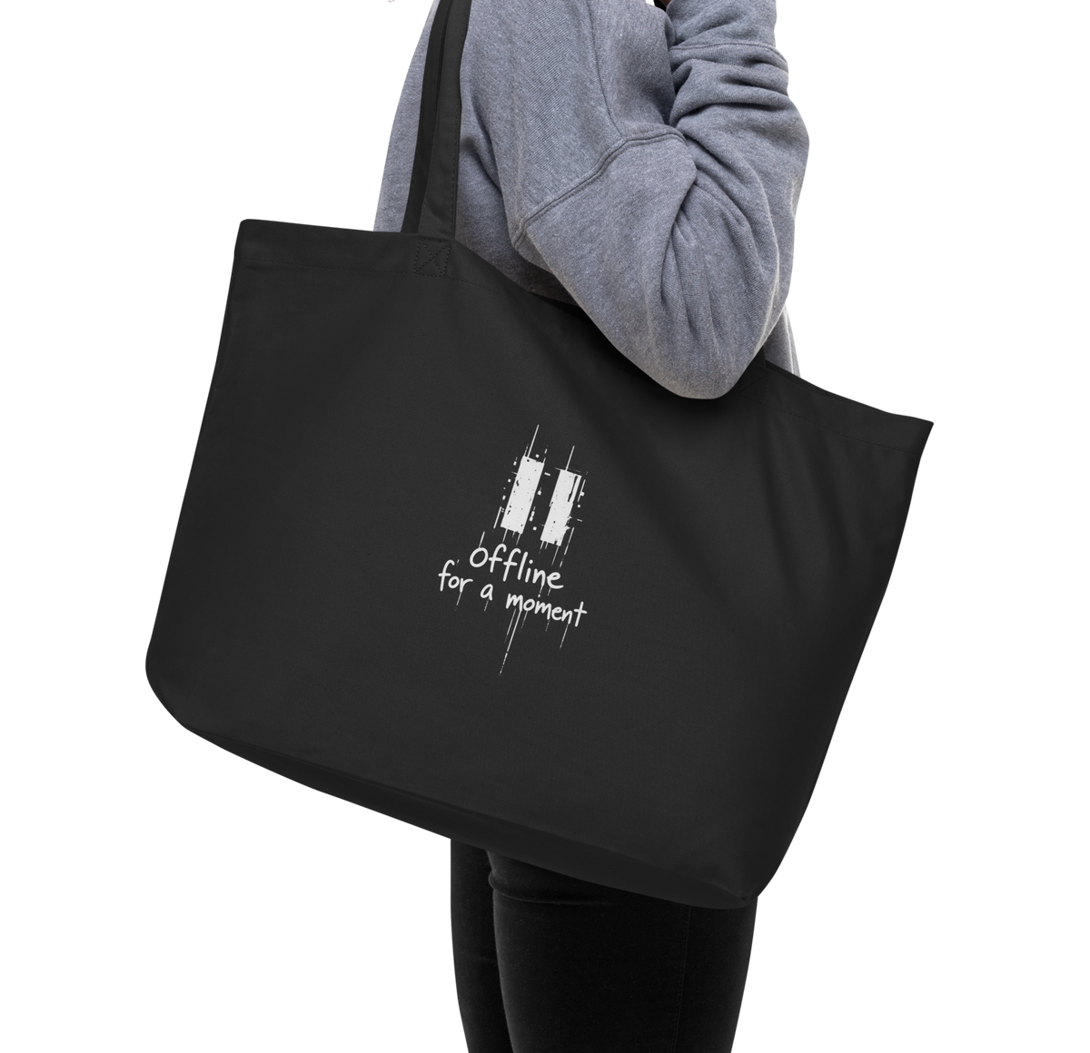 Black organic cotton tote bag with a white “Offline for a moment” graphic, carried over the shoulder.